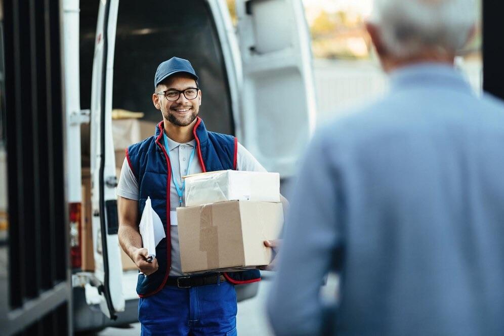 Smiling delivery person handing packages to a customer, representing SureBright’s shipping insurance that protects purchases from damage, loss, or theft.